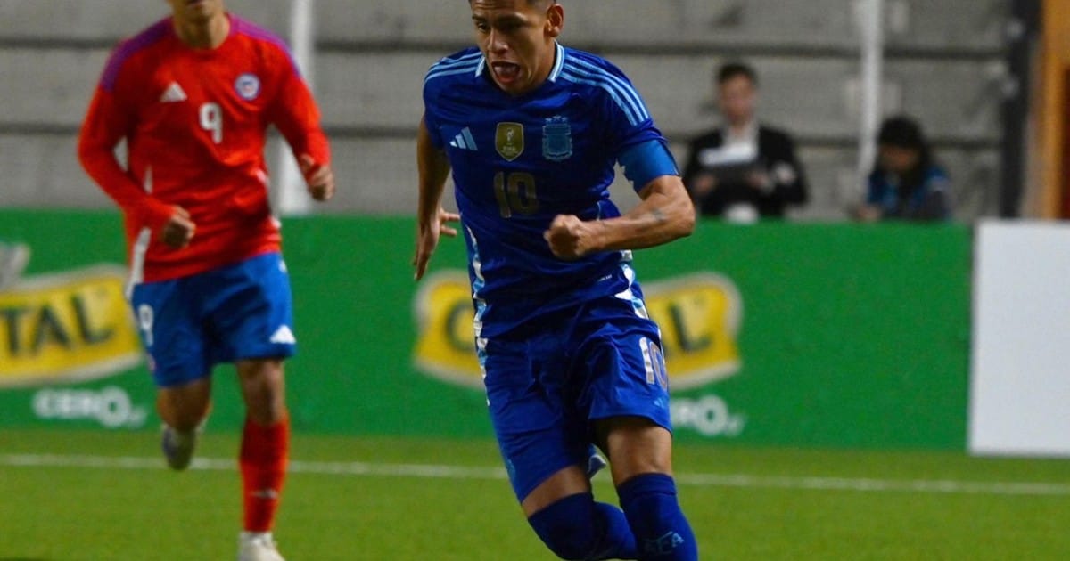 Jugador de la selección Argentina sub 20 de Fútbol en un estadio, con un jugador de la selección de Chile por detrás.