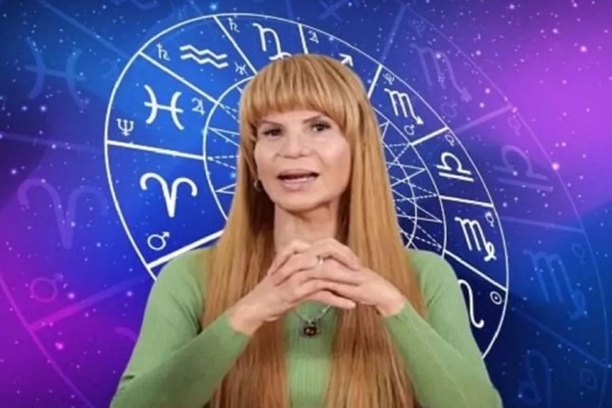 Imagen de Mhoni VIdente mostrando las cartas del tarot con un fondo con los signos astrológicos.